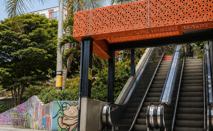 Las escaleras eléctricas de la Comuna 13 bajo su cubierta naranja, junto a muros pintados.