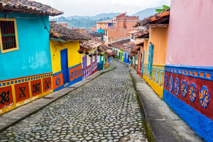 Calle empedrada de Guatapé bordeada de casas de colores con sus zócalos pintados.