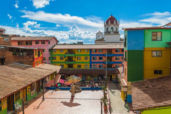 Plazoleta de Guatapé rodeada de fachadas de colores, con la torre de la iglesia al fondo.