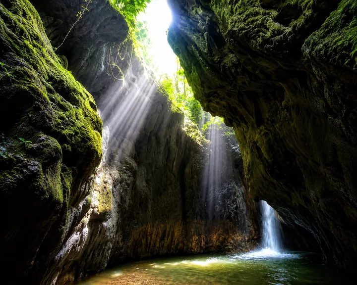 Interior de una caverna del cañón, con una cascada cayendo entre las rocas.