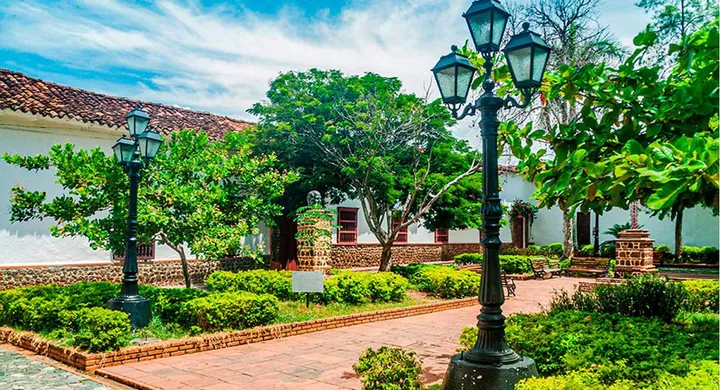 Parque arbolado de Santa Fe de Antioquia, con faroles antiguos y fachadas blancas coloniales.